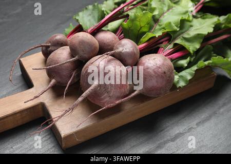 Many young beets with green leaves on dark textured table, closeup Stock Photo