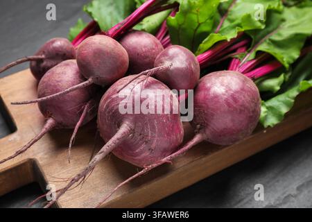 Many young beets with green leaves on dark textured table, closeup Stock Photo