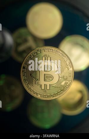 Cryptocurrency coins including Bitcoin scattered on a dark textured surface Stock Photo