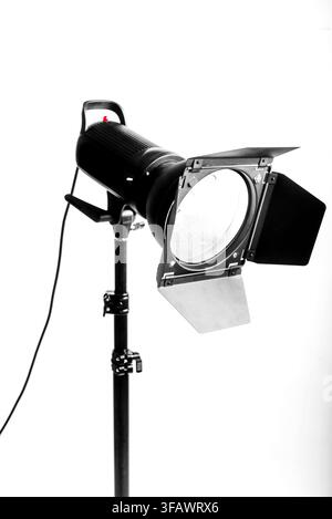Professional studio photography lighting equipment with barn doors on a metal stand against a clean white background. Stock Photo