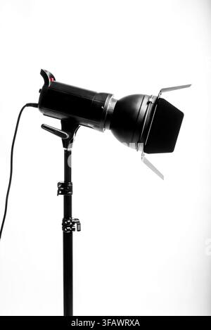Professional studio flash lighting equipment on a metal stand against a clean white background, photography gear concept. Stock Photo