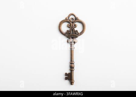 Vintage antique metal key with ornate decorative handle isolated on a clean white background, security and mystery concept. Stock Photo