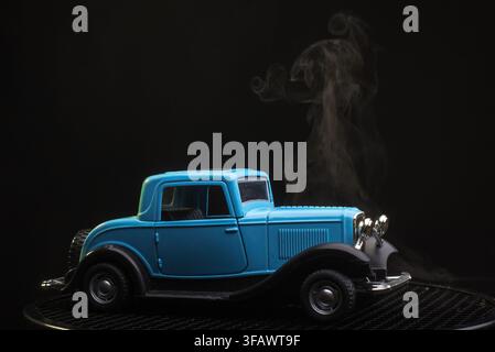 Vintage blue toy car in a smoky mysterious atmosphere on dark background Stock Photo