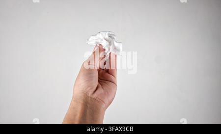 Asian man han holding a crumpled white tissue on white background Stock Photo