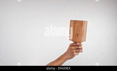 Hand Holding Small Wooden Cutting Board with Handle on white background Stock Photo
