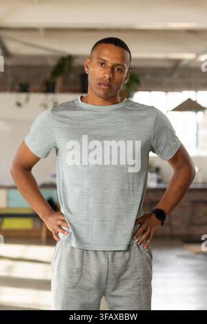 African American adult male standing in loft studio wearing gray loungewear, checking smartwatch Stock Photo