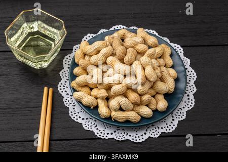 Roasted peanuts in shell served on blue dish Stock Photo