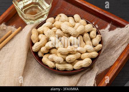 Roasted peanuts in shell served on blue dish Stock Photo
