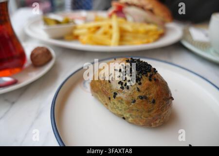 a freshly baked Turkish pogaca served on a white plate with black sesame seeds sprinkled on top Stock Photo