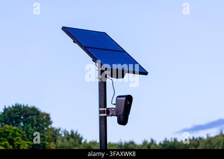 Solar powered automated license plate reader camera mounted on a pole with dual solar panels outdoors under a clear blue sky. Stock Photo
