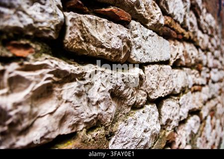 The rugged texture of an ancient masonry wall built from irregular fieldstones and weathered mortar. Stock Photo