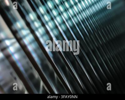Abstract close-up of light and shadow on textured glass with blue highlights and soft reflections, forming dynamic diagonal lines. Stock Photo