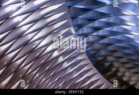 Abstract metallic interior ceiling with repeating folded panels in silver, gold and blue, modern architectural pattern. Stock Photo