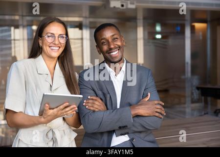 Portrait of happy multiethnic colleagues standing in corporate office Stock Photo