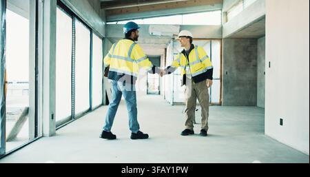 Handshake, happy and construction team at worksite for partnership, collaboration and agreement. Building development, civil engineering and men Stock Photo