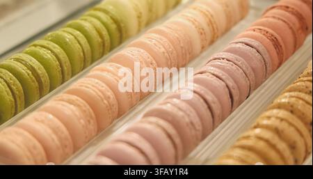 Colorful French macarons lined up in a pastry shop display tray, variety of pastel flavors, gourmet dessert presentation for commercial use. Stock Photo