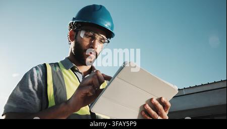 Development, engineer and man with tablet outdoor, building construction and stress for report error. Tech, serious person and engineering mistake Stock Photo