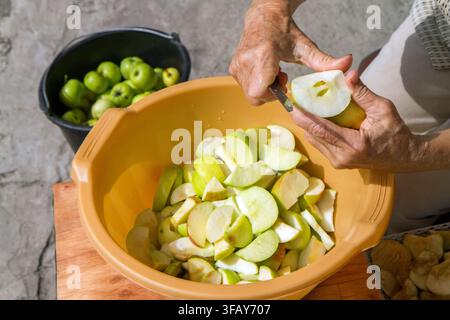 Cutting natural apples. Hands of an elderly woman. Canning fruits from the garden. Stock Photo