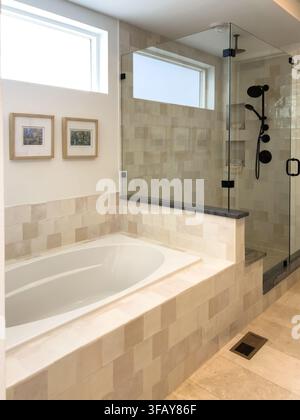 Parker, Colorado, USA-August 26, 2025 - A modern bathroom interior with a built in bathtub, glass shower enclosure, and neutral wall tiles. The space Stock Photo