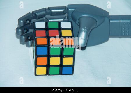 Blue Robotic Hand Holding Rubik's Cube, Artificial Intelligence and Problem Solving Concept Stock Photo