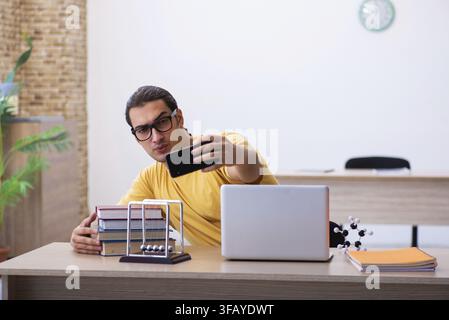 Young student using cell phone while preparing for exams Stock Photo