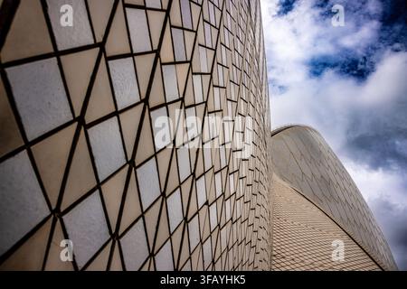Sydney Opera House close-up showing white tiled sails against dramatic cloudy sky, abstract modern architecture background with geometric pattern. Stock Photo