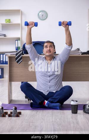 Handsome male employee doing exercises in office Stock Photo