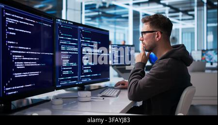Young Software Engineer Coding Secure Platform At Desktop In Office Workspace. Stock Photo