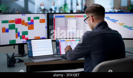 Agile Project Manager Updates Scrum Board And Checks Laptop Tasks. Stock Photo