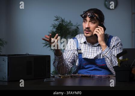 Young technician repairs computers in the workshop at night Stock Photo