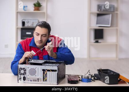 Young male mechanic repairs computer PC Stock Photo