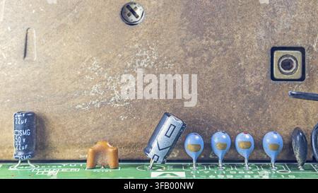 Macro close-up of vintage television circuit board with capacitors and ceramic components, detailed electronic parts on brown and green PCB background Stock Photo