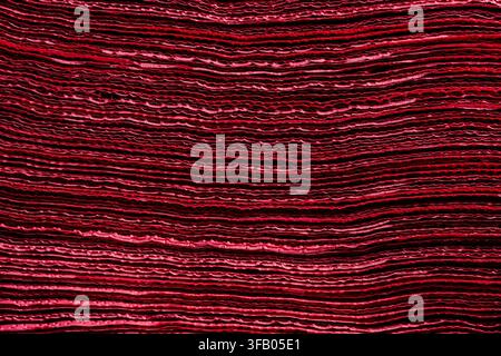 Red textured background of layered wavy paper sheets. Close up of dark red pleated material layers creating vibrant textured abstract background for d Stock Photo