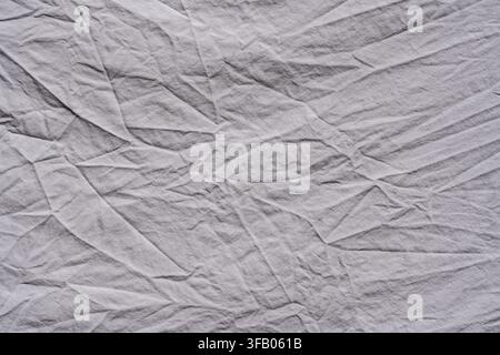Top view of light gray crumpled fabric texture as abstract background, close up. Simple minimalist textile backdrop for fashion, lifestyle and organic Stock Photo
