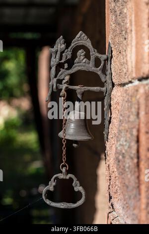 Vintage cast iron doorbell with small bell and chain. Antique metal doorbell with small decorative bell and pull chain mounted on brick wall, close up Stock Photo