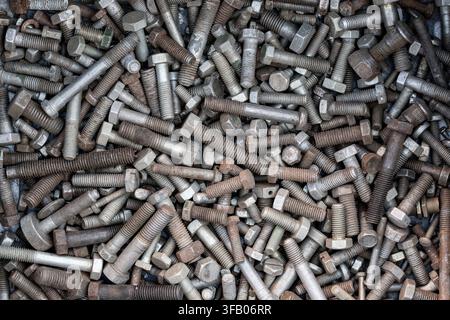 Background of old rusty mixed metal bolts and screws. Pile various vintage steel bolts, screws and fasteners. Concept of construction waste, scrap met Stock Photo