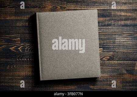 Blank linen book cover mock up on wooden background. Top view of grey fabric notebook photo album or book with hard linen cover template on textured d Stock Photo
