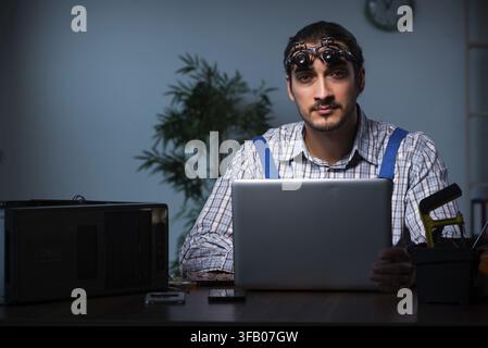Young technician repairs computers in the workshop at night Stock Photo