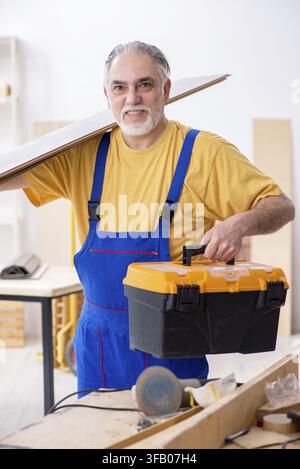 The old male carpenter works in the workshop Stock Photo