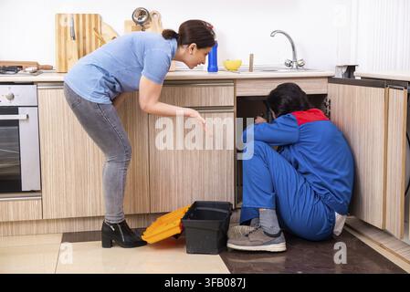The young male mechanic repairs the faucet Stock Photo
