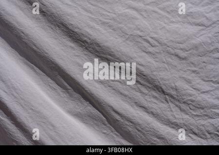 Top view macro texture of crumpled grey fabric. Full frame close up background of soft crumpled grey or lavender textile material with natural folds c Stock Photo