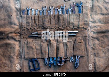 Vintage tool roll organizer with old wrenches and pliers, close up. Flat lay macro shot of weathered canvas tool roll organizer filled with various ol Stock Photo