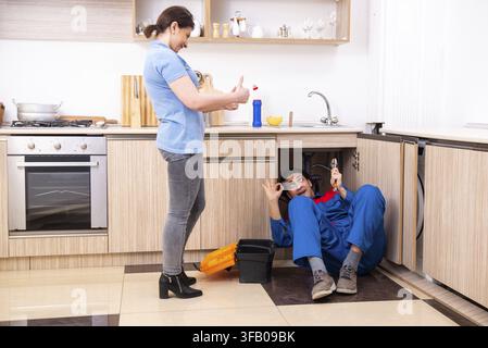The young male mechanic repairs the faucet Stock Photo