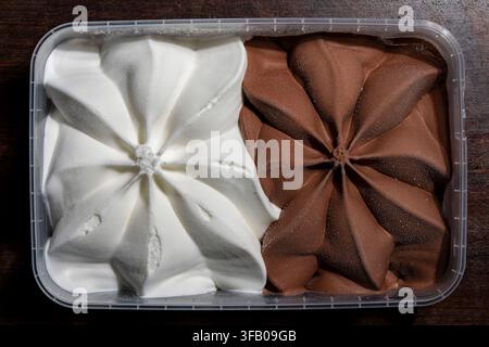 Top view of chocolate and vanilla ice cream container, close up. Plastic container filled with half white vanilla and half brown chocolate ice cream s Stock Photo