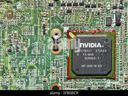 Close-up of an NVIDIA GPU chip mounted on a green laptop motherboard, showing microchips, circuits, and electronic components, representing computer h Stock Photo