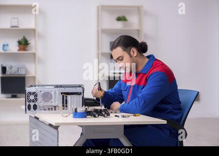 Young male mechanic repairs computer PC Stock Photo