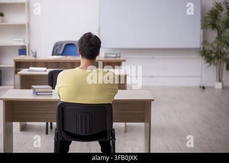 Young student teacher sitting in classroom Stock Photo