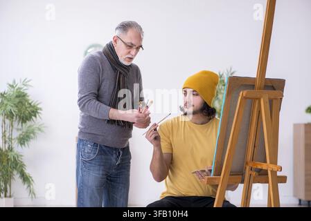 Young man takes lessons from an experienced painter Stock Photo