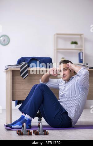 Handsome male employee doing exercises in office Stock Photo