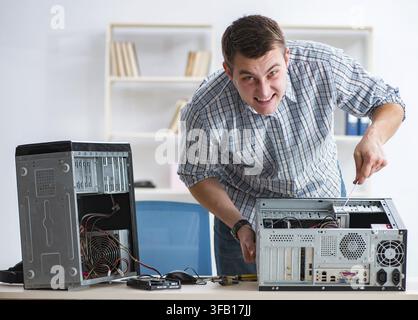 The young technician repairs computers in the workshop Stock Photo